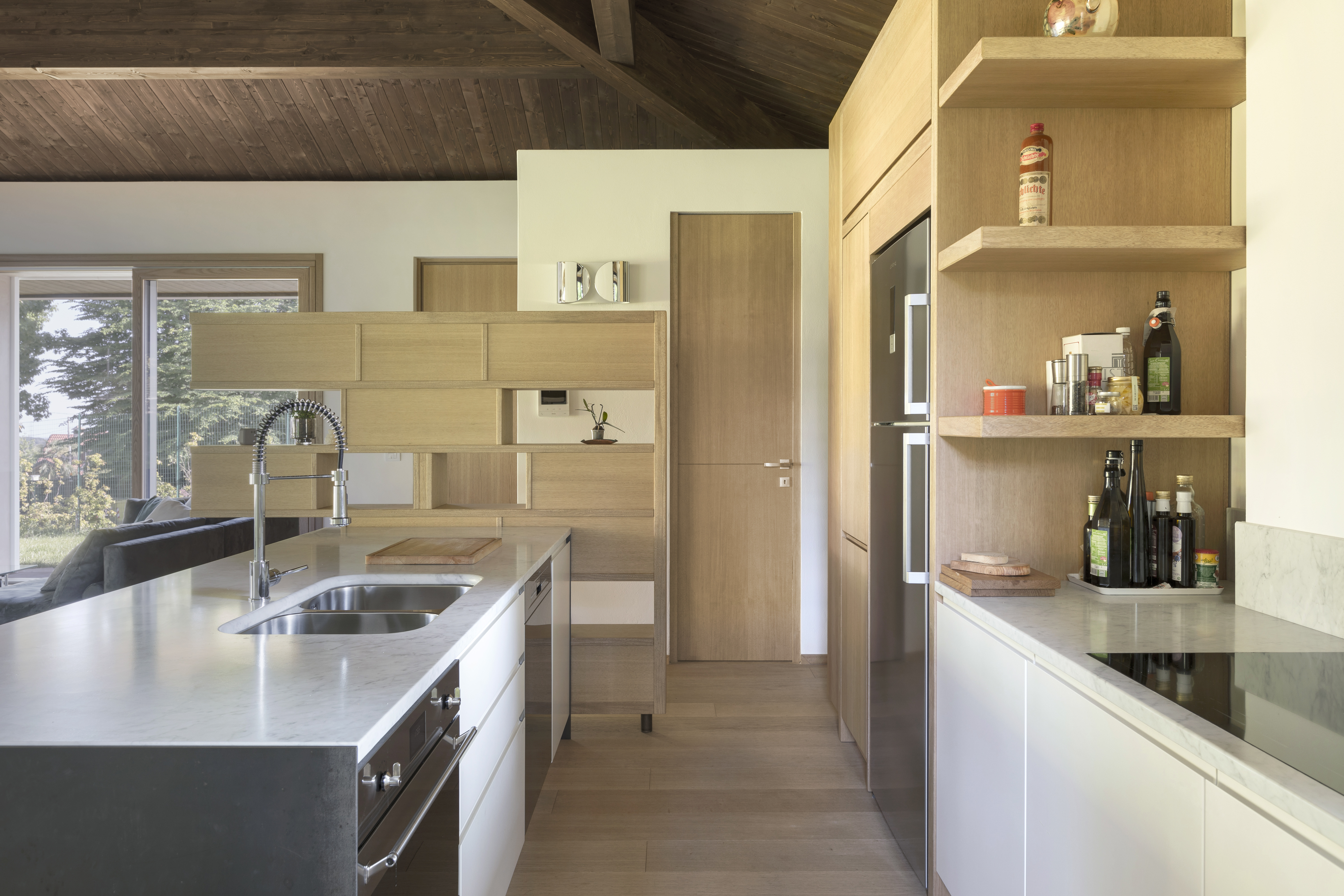 Interni: cucina in openspace, grandi serramenti in legno con affaccio sul verde esterno 